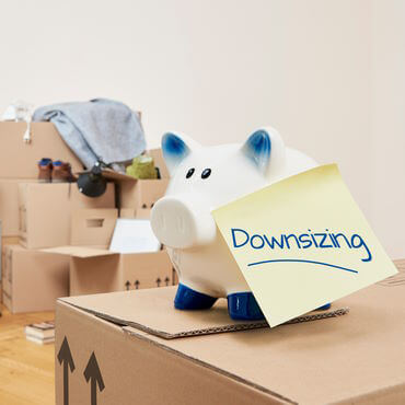 A piggy bank on top of moving boxes with a note that says downsizing.