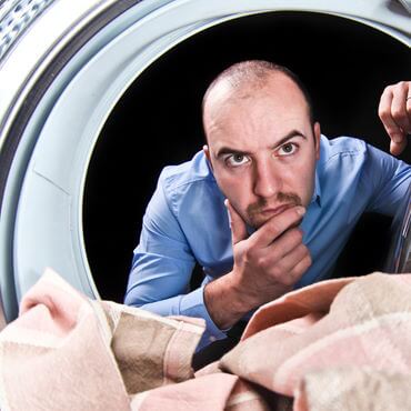 Man with puzzled look on his face looking into dryer